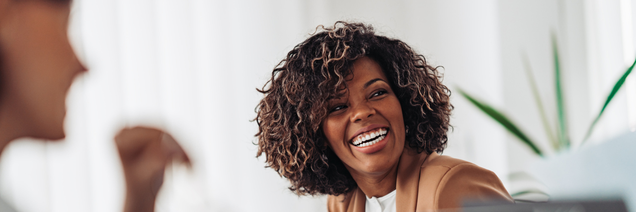 KHN: With a Diagnosis at Last, Black Women With ADHD Start Healing A Black woman laughing in an office meeting