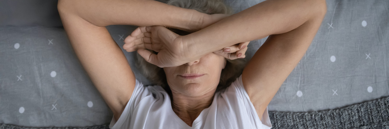 Struggling With Chronic Insomnia for Much of Your Life Woman covering her face with her hands in bed