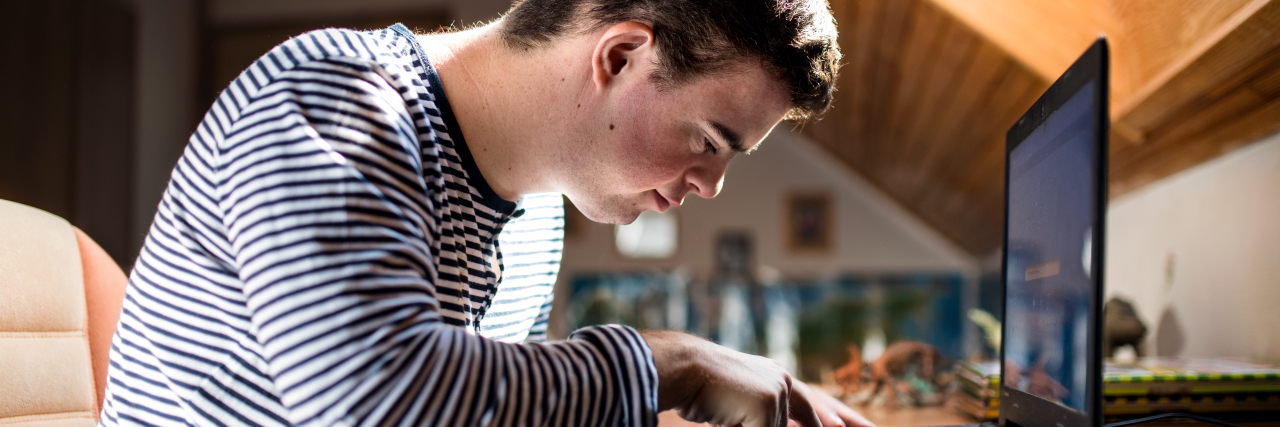 Now Is the Time to Fix the Barriers to Disability Employment Man with Down syndrome typing on computer.