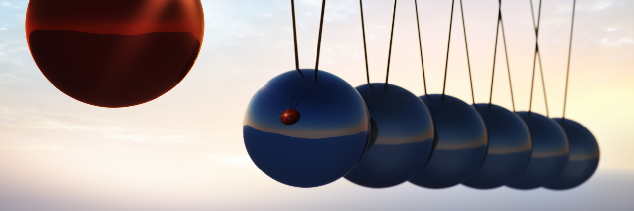 The Depression Pendulum That Swings Back and Forth silver and one red metal balls on a white background