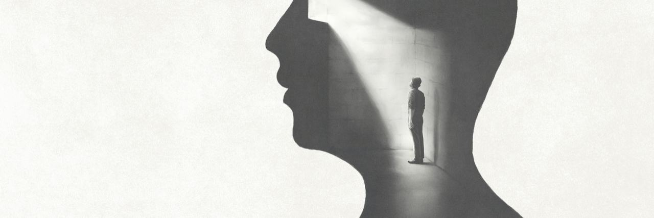 What It's Like Watching a Young Man Develop Schizophrenia A silhouette of a man's profile. In his head, is another man trapped in a dark room with one light