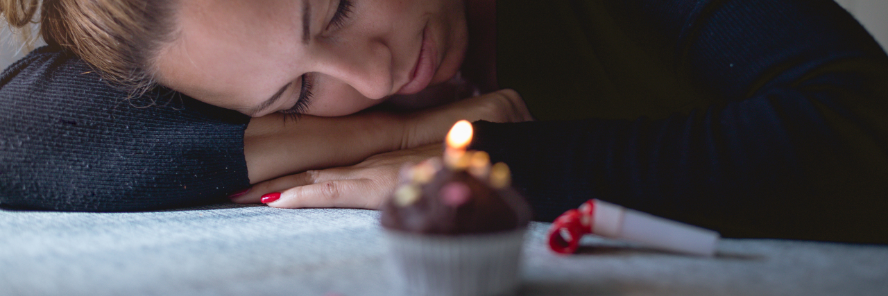Person sad leaning on the counter with a cupcake near them