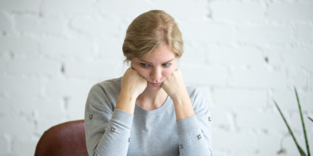 A photo of a white woman with blonde hair sitting at her desk
