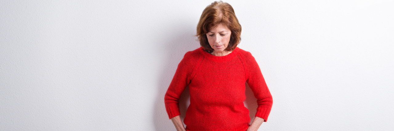 Start Breaking Mental Health Stigma by Thinking About Your Words Middle-aged white woman in a red sweater looking down