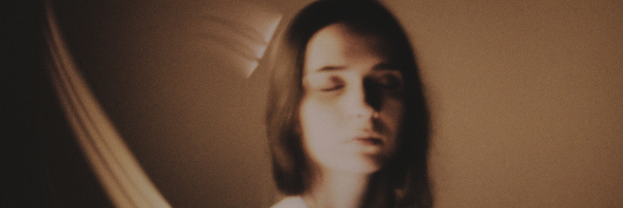 How Dissociation Affects My Pain Levels With PTSD Young woman with her eyes closed, blurred background