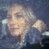 Sad woman sitting in the car in rain.