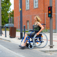 Woman in wheelchair crossing the street.