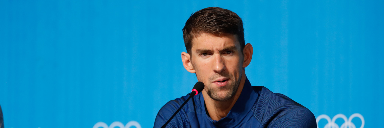 Michael Phelps speaking at a podium at the 2016 Rio Olympics
