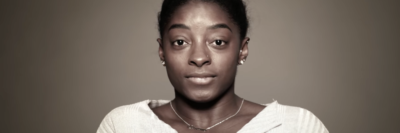 Simone Biles' Withdrawal From Olympics is a Win for Trauma Survivors Screenshot of Simone Biles looking into camera on Facebook Watch with tears in her eyes