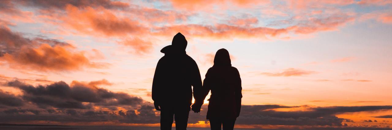 Couple holding hands at sunset.