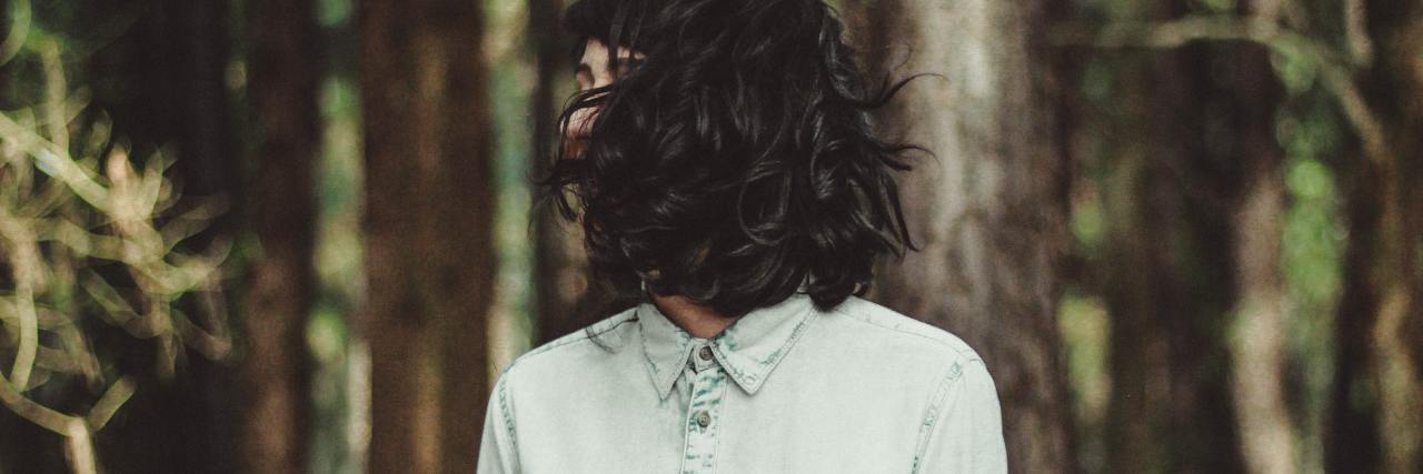 photo of a woman with dark hair in a forest, her hair covering her face