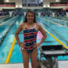 Becca Meyers wearing a red, white and blue stars swimsuit at a competition with pool in background.