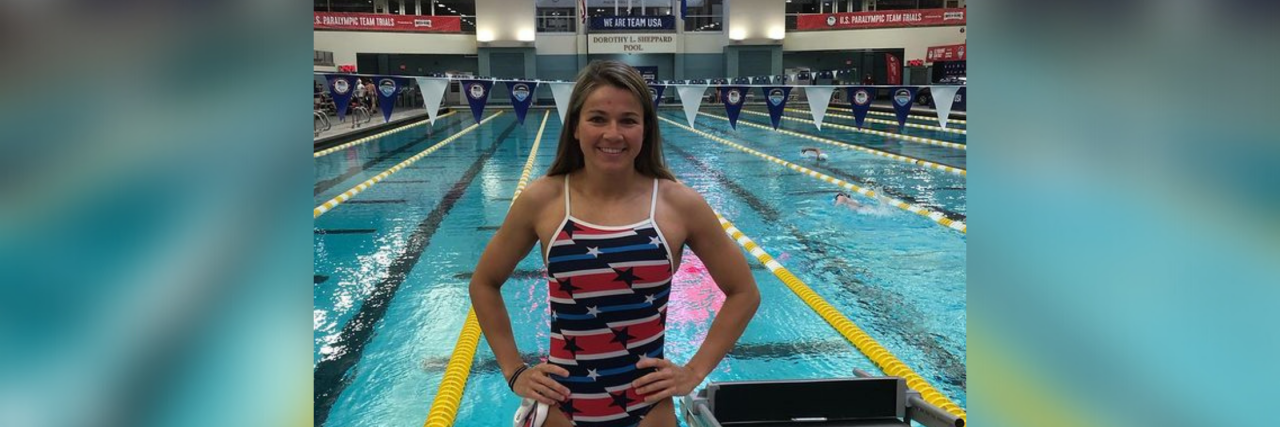Deaf-Blind Swimmer Becca Meyers Withdraws From Paralympics Becca Meyers wearing a red, white and blue stars swimsuit at a competition with pool in background.