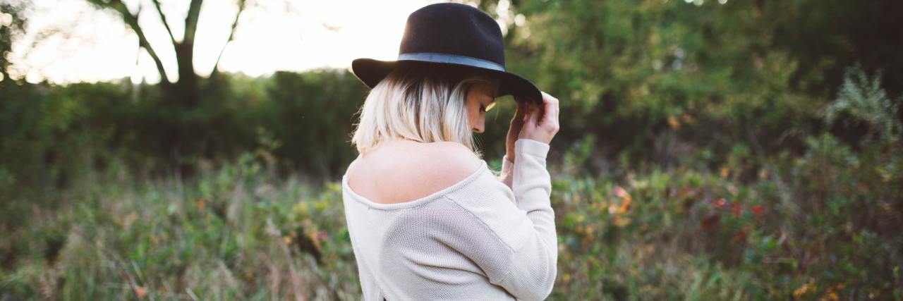 Taking What We Learned in 2020 Into the 'New Normal' Post-COVID-19 Woman standing outside in the grass with a black hat covering her face