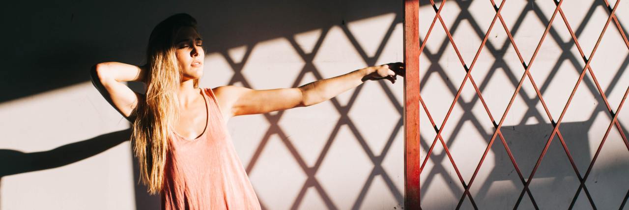 Struggling to Socialize Post-Lockdown With Complex PTSD and ADHD photo of a woman hanging on to a fence post with light and shadow