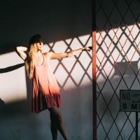 photo of a woman hanging on to a fence post with light and shadow