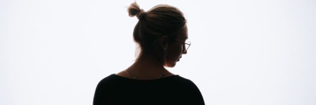photo of a woman in silhouette against white background, looking down and to the side in stress or sadness