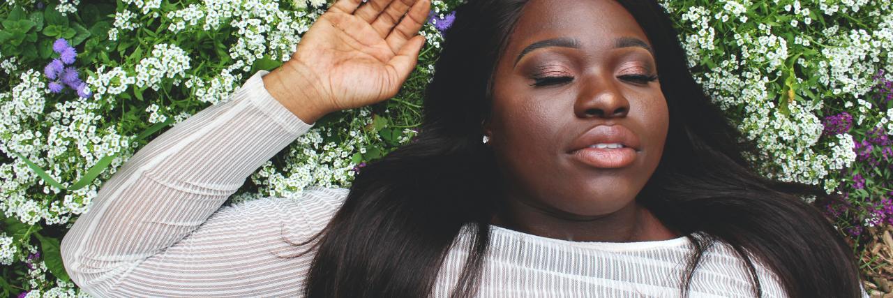 Assuming Only White Girls Get Eating Disorders Is Harming Black People photo of a woman lying down on white flowers with her eyes closed