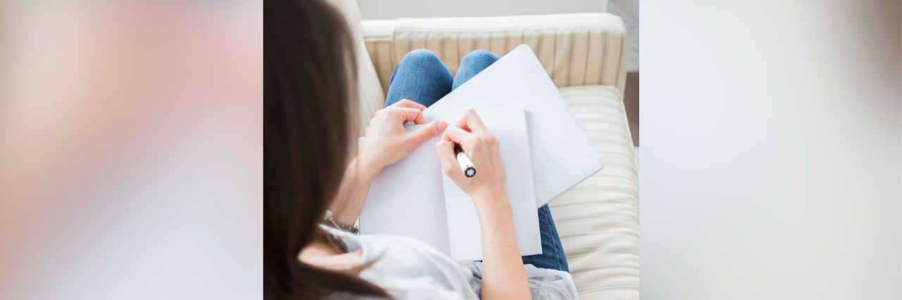Woman writing in journal on couch