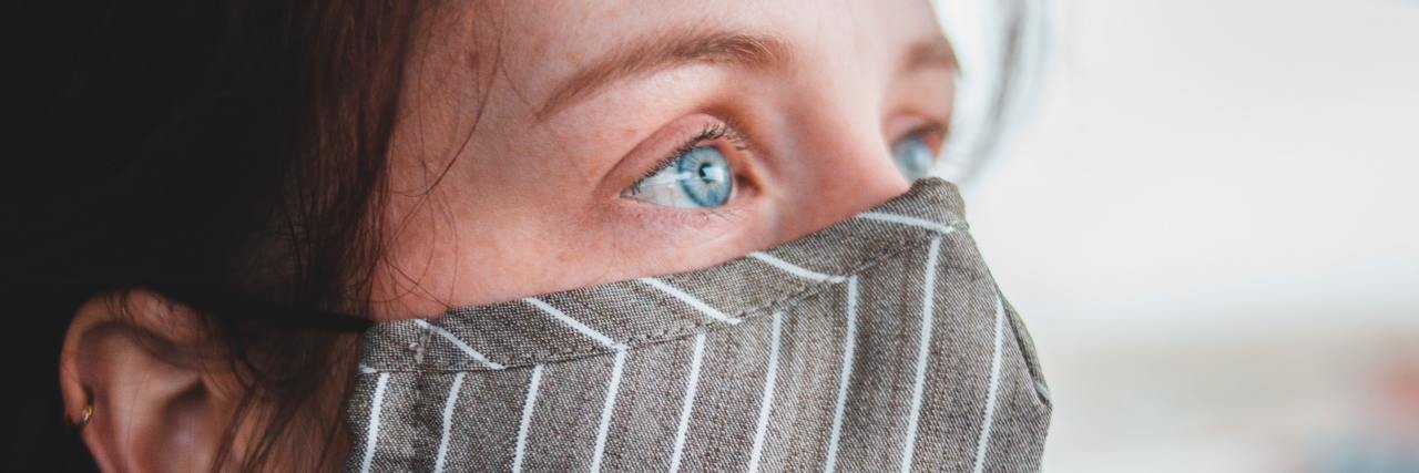 How to Cope With Post-Lockdown Social Anxiety photo of a person wearing a striped face mask and who has tearful eyes