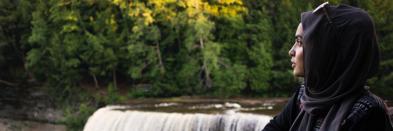 How I'm Coping With Menopause as Someone With Bipolar Disorder A Muslim woman standing by a waterfall looking off into the distance