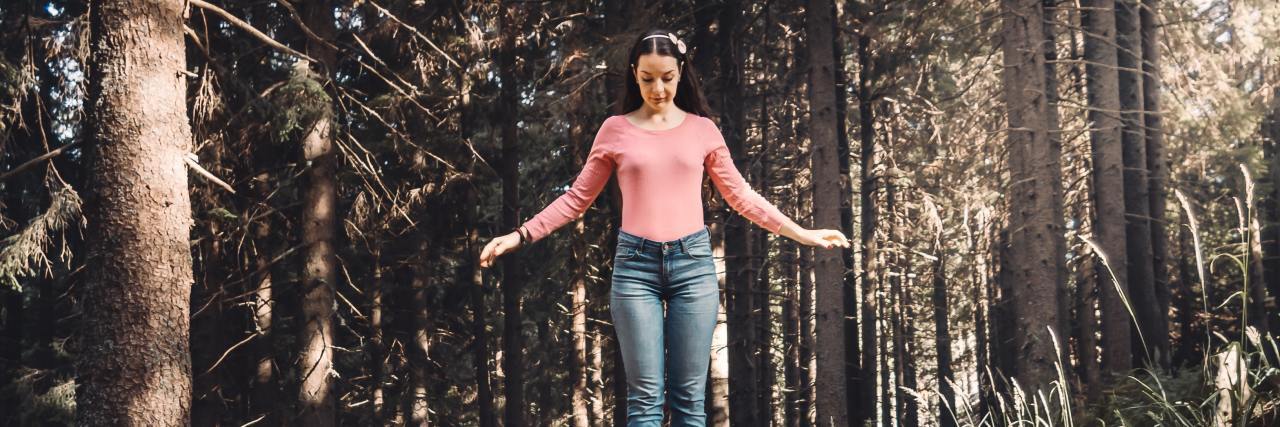 Accepting Your Limits With Bipolar Disorder photo of a woman balancing on a fallen tree in a forest