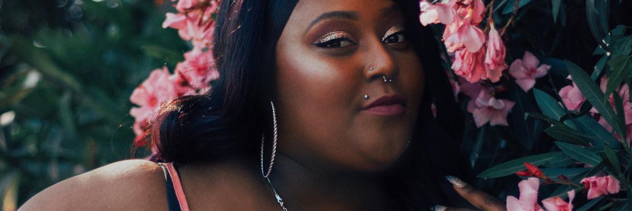 Finding Freedom From the Influence of Diet Culture photo of a woman smiling and posing next to flowers