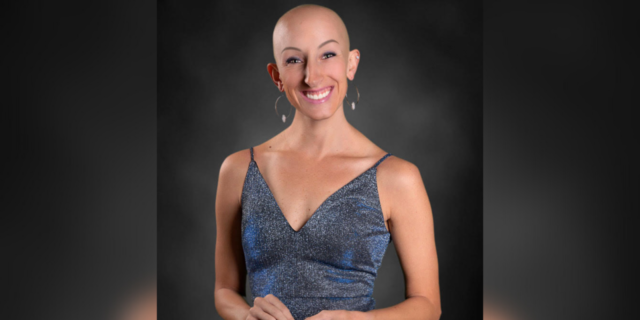 Lindsay, a woman with alopecia who is bald and wearing a blue dress.