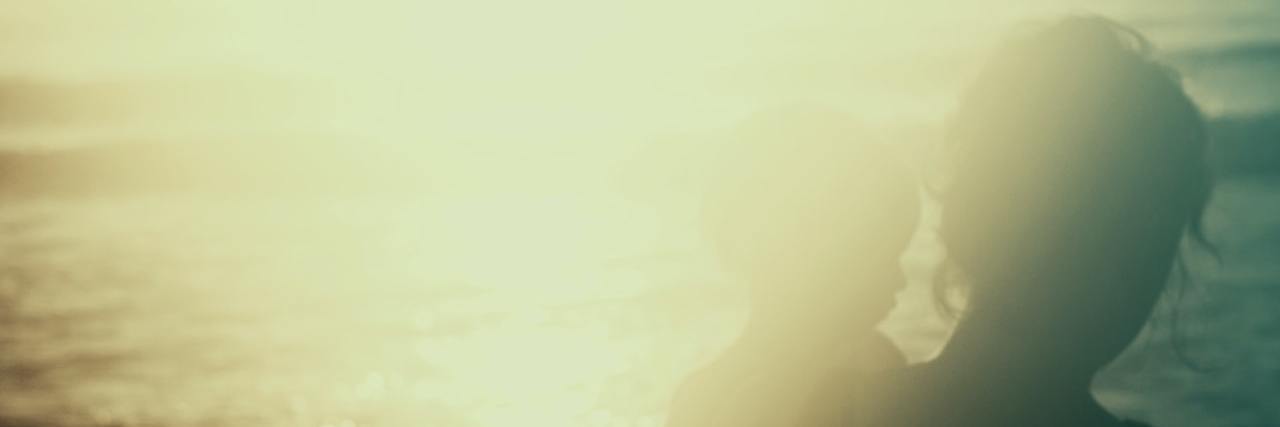 Exploring Life and Loss as the Parent of a Child With Down Syndrome Mother and child silhouette in front of water