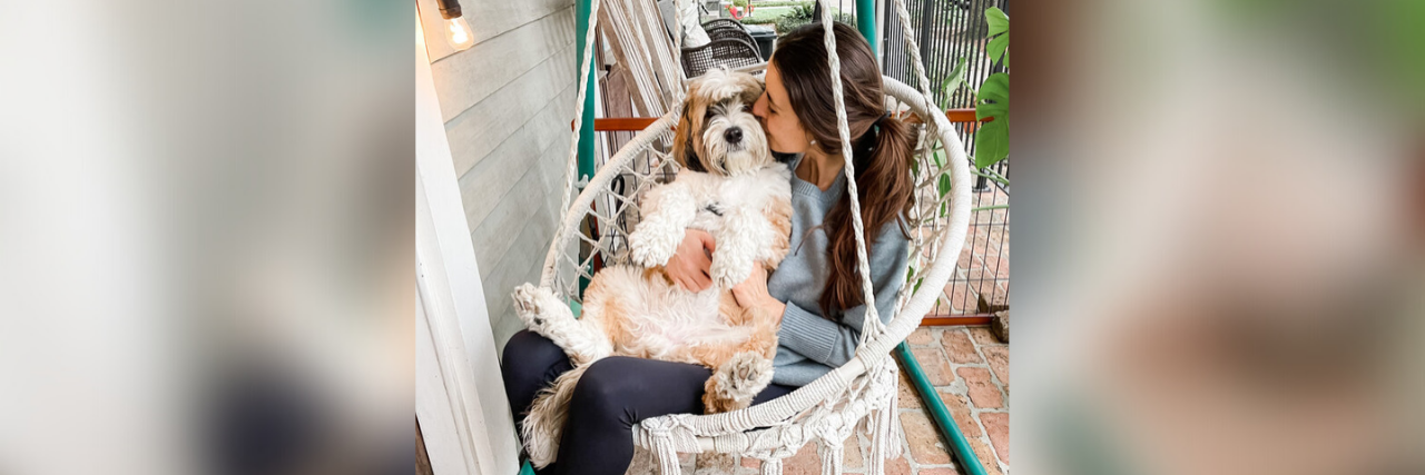 Natalie sitting in a porch hammock swing with her dog.