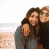 2 young women with arms around each other, smiling