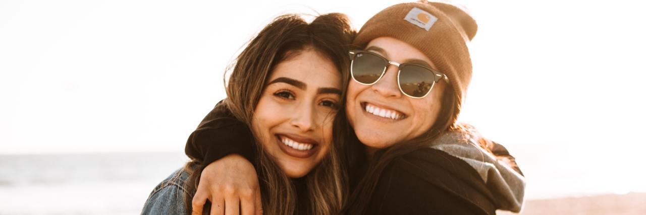 Lifting COVID-19 Mask Mandates Has Helped Me Emotionally Connect 2 young women with arms around each other, smiling