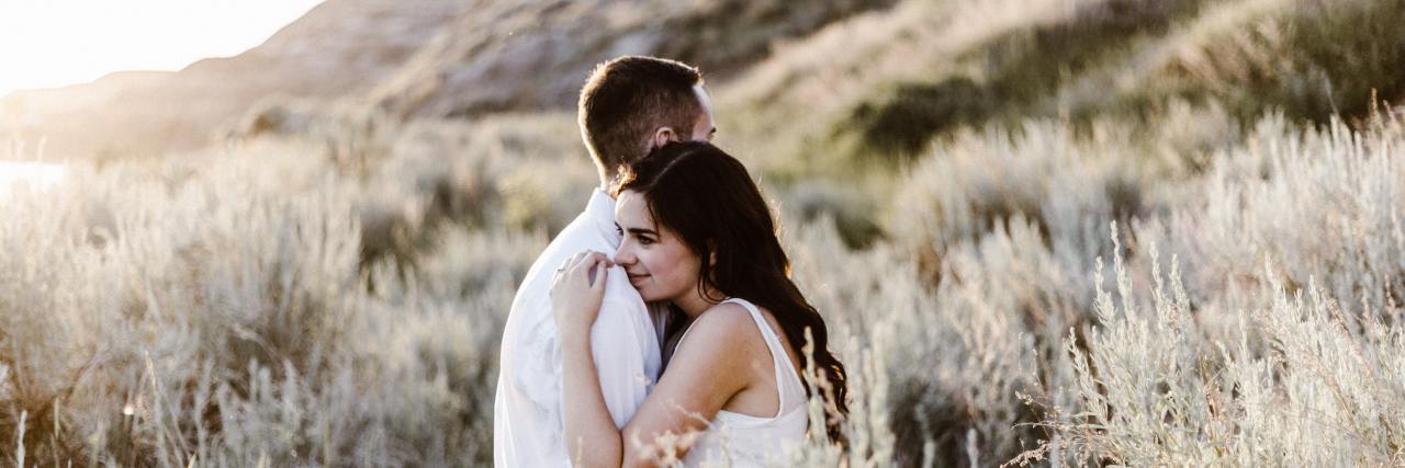 Codependency and Toxic or Abusive Relationships After Trauma photo of man and woman hugging in the desert with mountains behind them