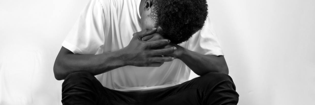 Trauma: How Sibling Relationships are Affected by Cutting Off Parents black and white photo of a man resting head in his hands, his arms on his legs, looking upset