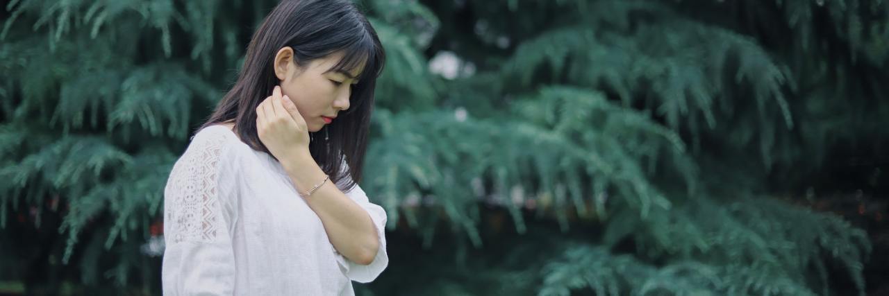 When You Can't Turn to Parents for Emotional Support photo of a young woman looking down and sad in profile view against backdrop of trees