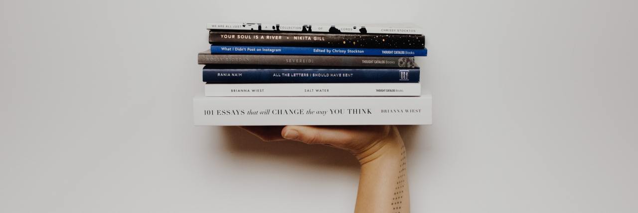 4 Must-Read Books That Portray Mental Illness Accurately A hand holding a stack of books