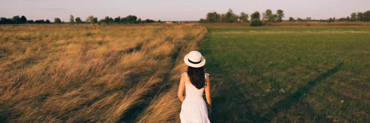 How to Describe Borderline Personality Disorder to Loved Ones photo of a woman walking along a boundary between two fields away from the camera