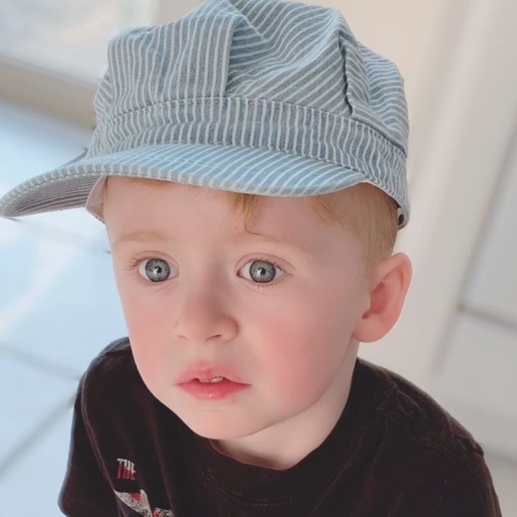 Jacquelyn's son wearing a blue train engineer's cap.