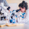 Scientist in lab doing research and using lab machines, test tubes, microscope and laboratory equipment