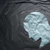 Person head shaped paper on black torn paper background.