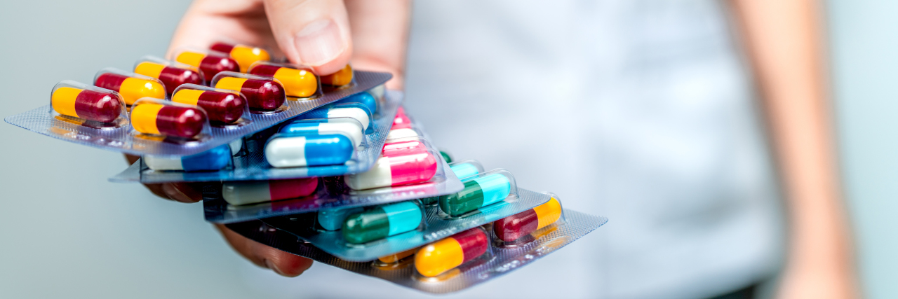 What It Feels Like to Be on Long-Term Antibiotics Person holdingg packs of antibiotics.