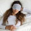 a woman laying in bed with a sleep mask on
