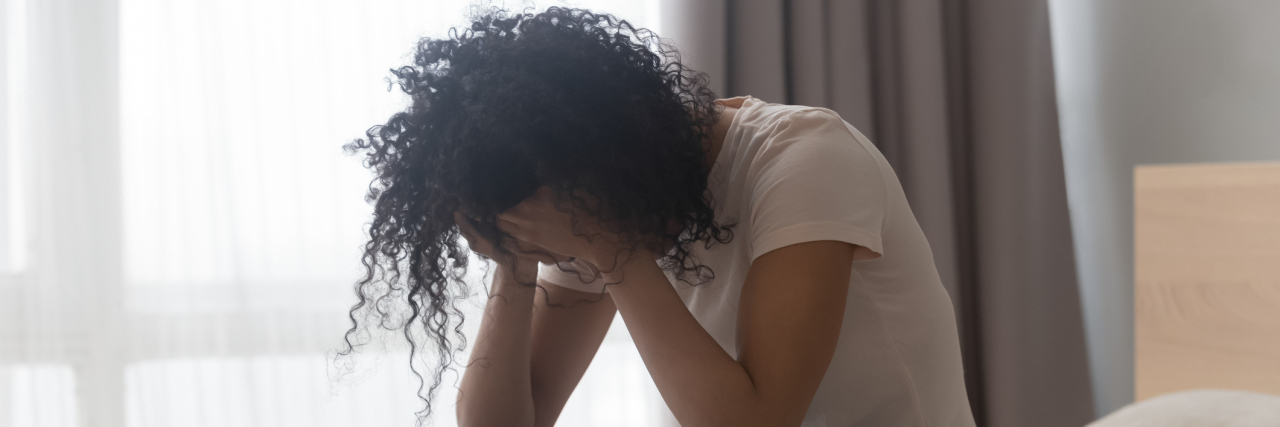 What Feeling Rejection Is Like With Borderline Personality Disorder Young Black woman sitting on her bed crying, hands to her face