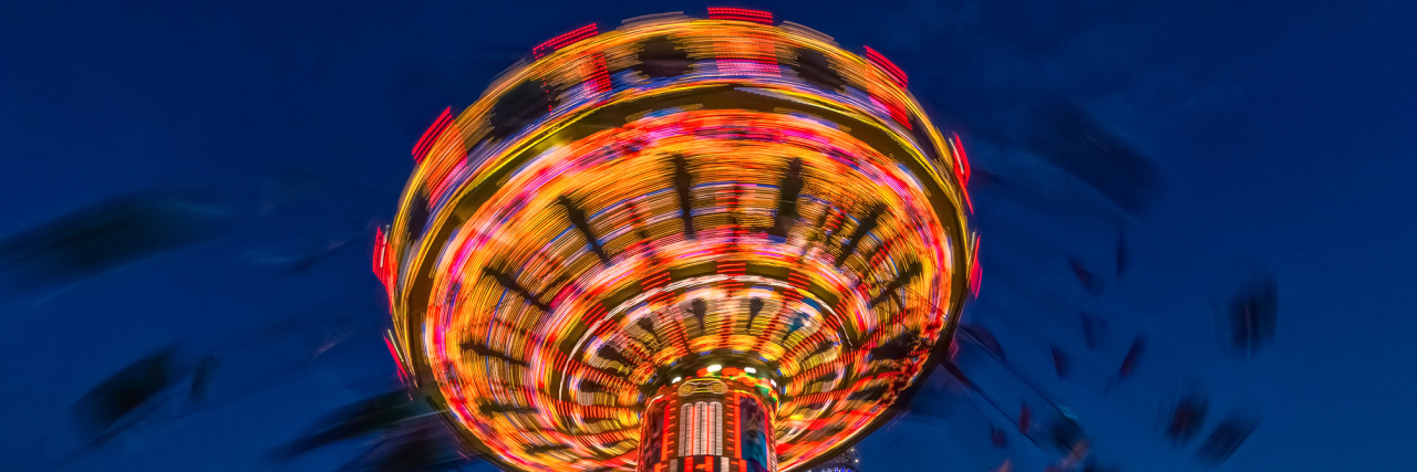 OCD Is Like a Ride That Never Stops Spinning in Your Mind Carousel lit up at night with bright colors and silhouettes of people swinging rapidly around