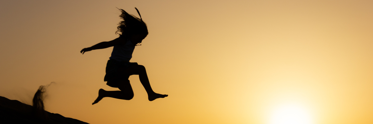 Girl jumping in the air at sunset.