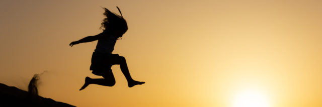 Girl jumping in the air at sunset.