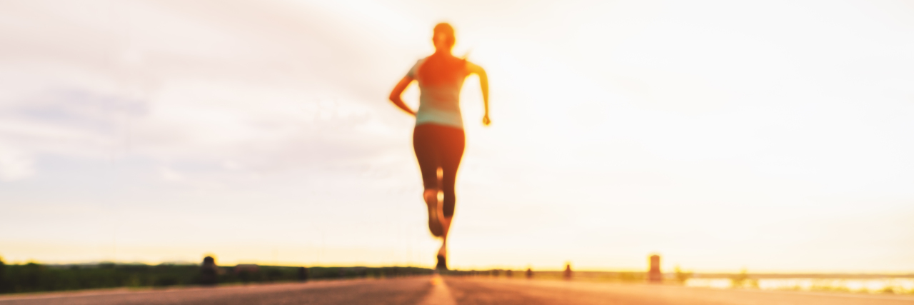 The Struggles of Anorexia When You Have a Disability Woman jogging down a road at sunset.