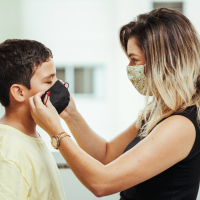 Mother helping son put on a mask.