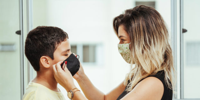 Mother helping son put on a mask.