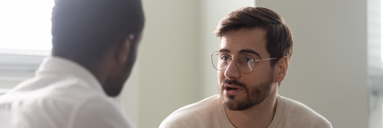 A young man in glasses talking to his doctor